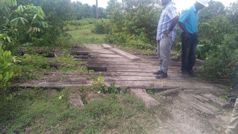 Technical personnel inspecting a dilapidated structure in the farming area.